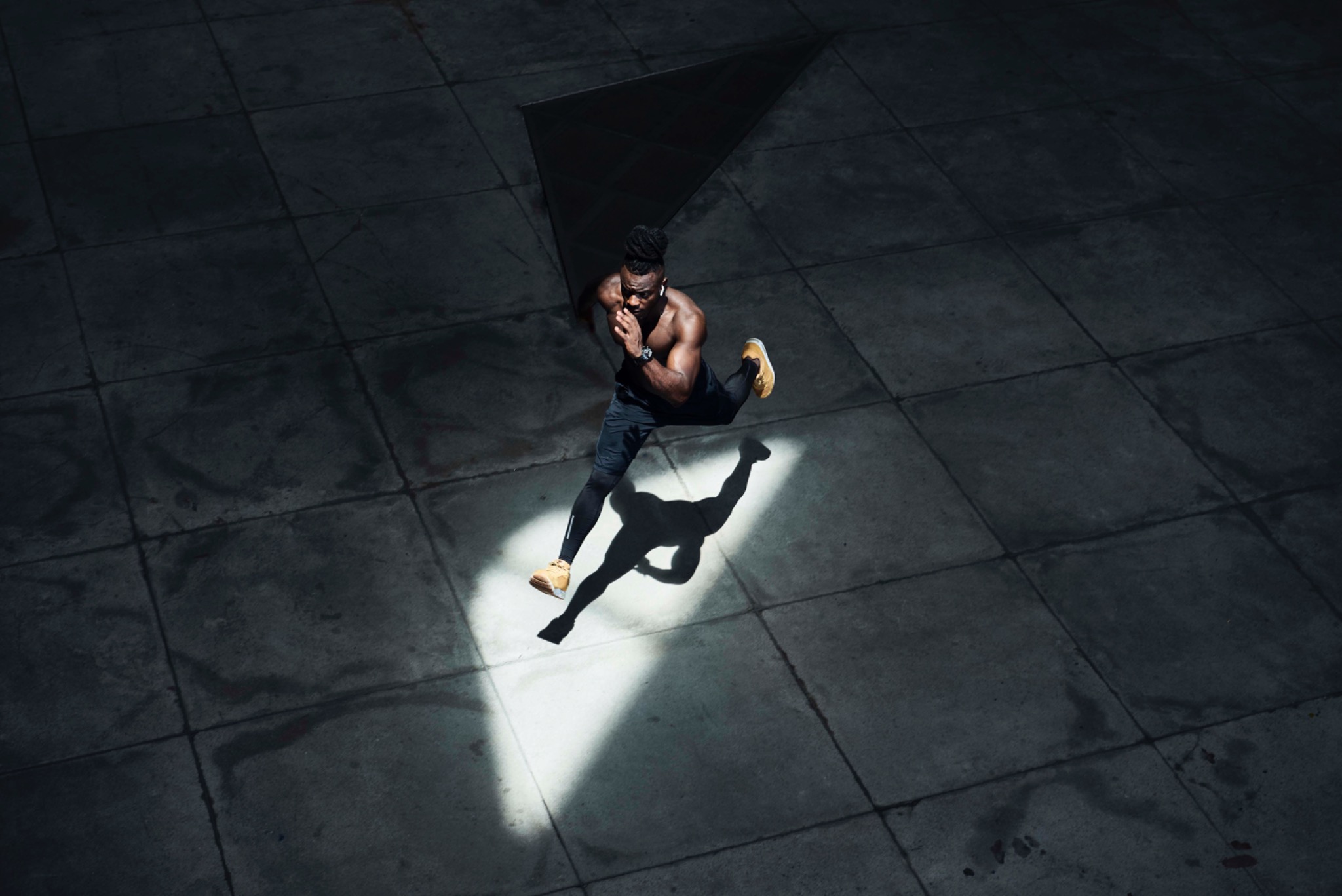 Runner seen from above, crossing a shaft of light